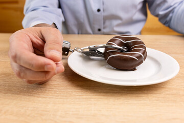A man is handcuffed to a chocolate donut. Passion for sweets.