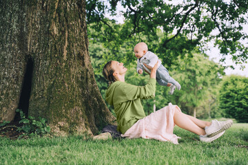 Mother and baby. Concept of natural maternity and motherhood. Beautiful woman and little baby happy together in green nature background. Loving mom with child outdoors.