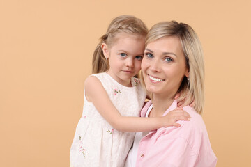 Family portrait of happy mother and daughter on beige background