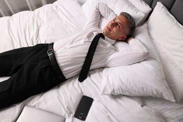 Businessman in office wear resting on bed indoors, above view