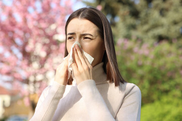 Woman with napkin suffering from seasonal allergy on spring day