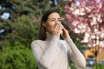 Woman with napkin suffering from seasonal allergy on spring day