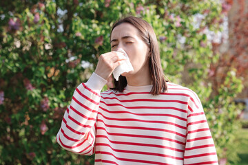 Woman with napkin suffering from seasonal allergy outdoors