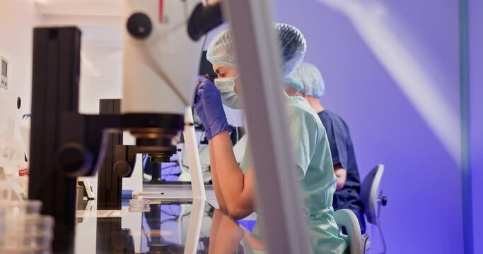 An embryologist conducting artificial fertilization of a human egg with specialized equipment in a laboratory setting. Laboratory worker examining samples under microscope in clinic.