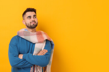 Smiling man in warm scarf on yellow background. Space for text