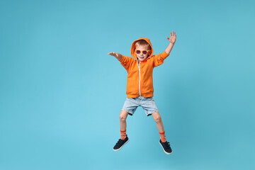 Happy little boy dancing on light blue background. Space for text
