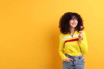 Beautiful woman with lollipop on yellow background, space for text