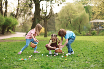 Fototapeta premium Easter celebration. Cute little children hunting eggs outdoors