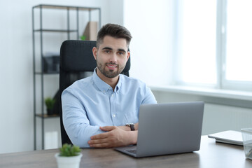 Happy young programmer working with laptop in office