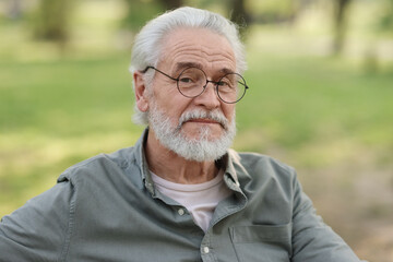 Portrait of happy grandpa with glasses in park