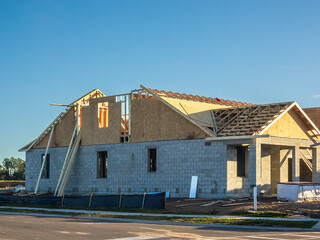 Side and partial rear of a bi-level single-family house under construction by a new street and...