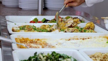 Customers serve themselves at a buffet with diverse and delicious dishes. Perfect for culinary stock media.