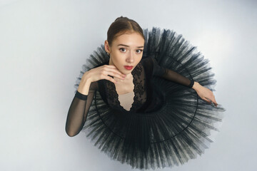 portrait of a young ballerina in a black tutu dancing with her hands moving top view, immersion in...