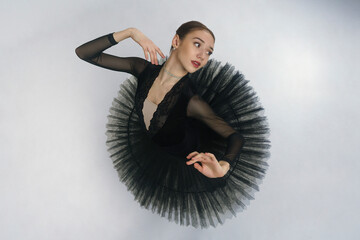 portrait of a young ballerina in a black tutu dancing with her hands moving top view, immersion in...