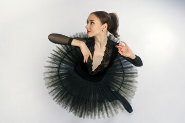 portrait of a young ballerina in a black tutu dancing with her hands moving top view, immersion in...
