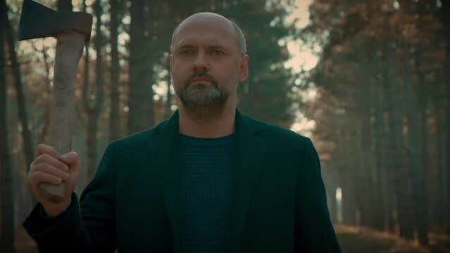 Serial maniac with axe in forest looking someone to kill. Bloody killer, murderer, madman walking through woods. Maniac Murder and crime, Halloween horror day concept