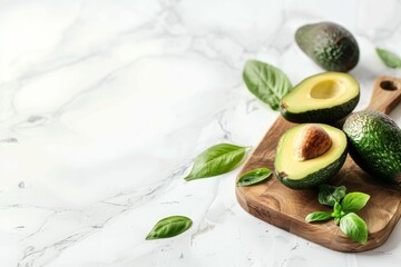 Fresh avocado with leaves on a wooden cutting board on a white kitchen background with copy space.