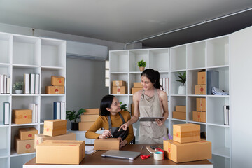 Female entrepreneurs packing boxes and managing order in home office. Concept of small business, ecommerce, and online retail