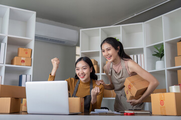 Excited female entrepreneurs celebrating successful online order in home office. Concept of small business, ecommerce, and achievement