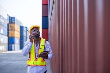 Black engineer in warehouse inspecting goods at industrial container yard