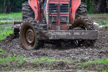 selective tractor plowing soil in rice fields It's about to be rice planting season in the rice fields. It's almost rainy season in the rice fields of