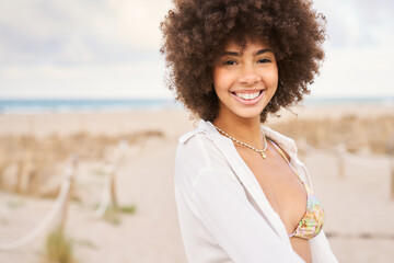 A woman with curly hair is smiling and wearing a bikini top