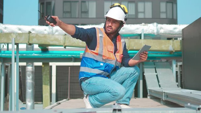 Engineer inspects water heater pump system and hot water tank on industrial roof