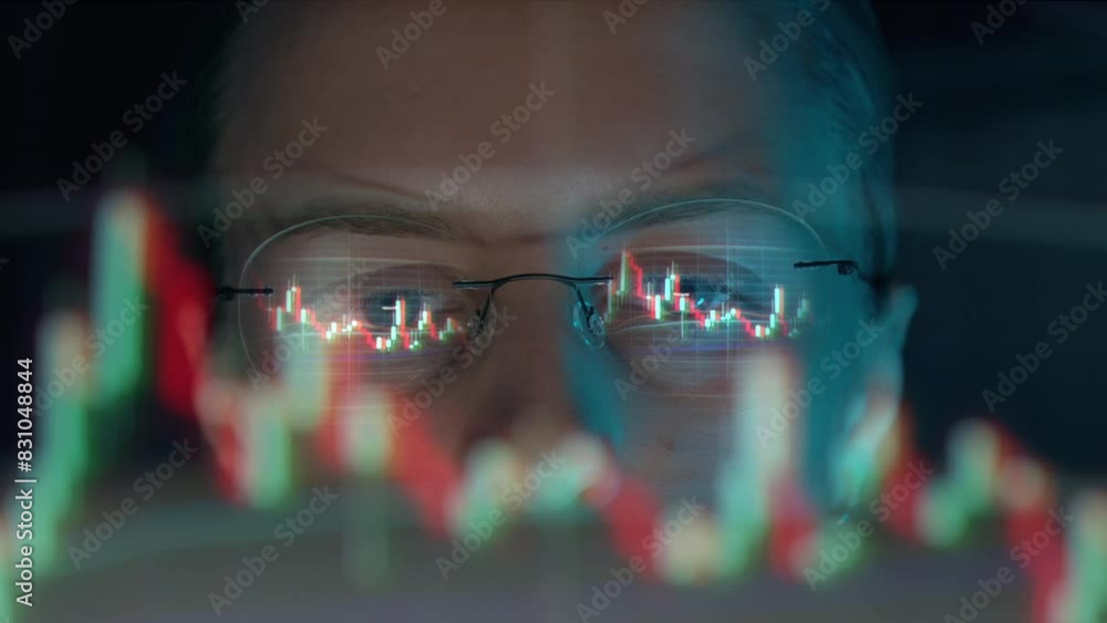 Poster trader wearing glasses is working on laptop computer. screen with stock market charts and bitcoin bt