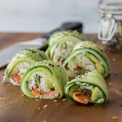 Cucumber sushi topped with everything bagel seasoning on a wooden board.