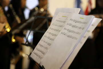 Music score on music stand with musical band in the background. Musical notes. Group of musicians....