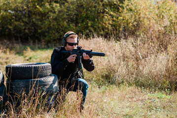 Fototapeta premium A man with a machine gun in his hand undergoes military training and learns to shoot.