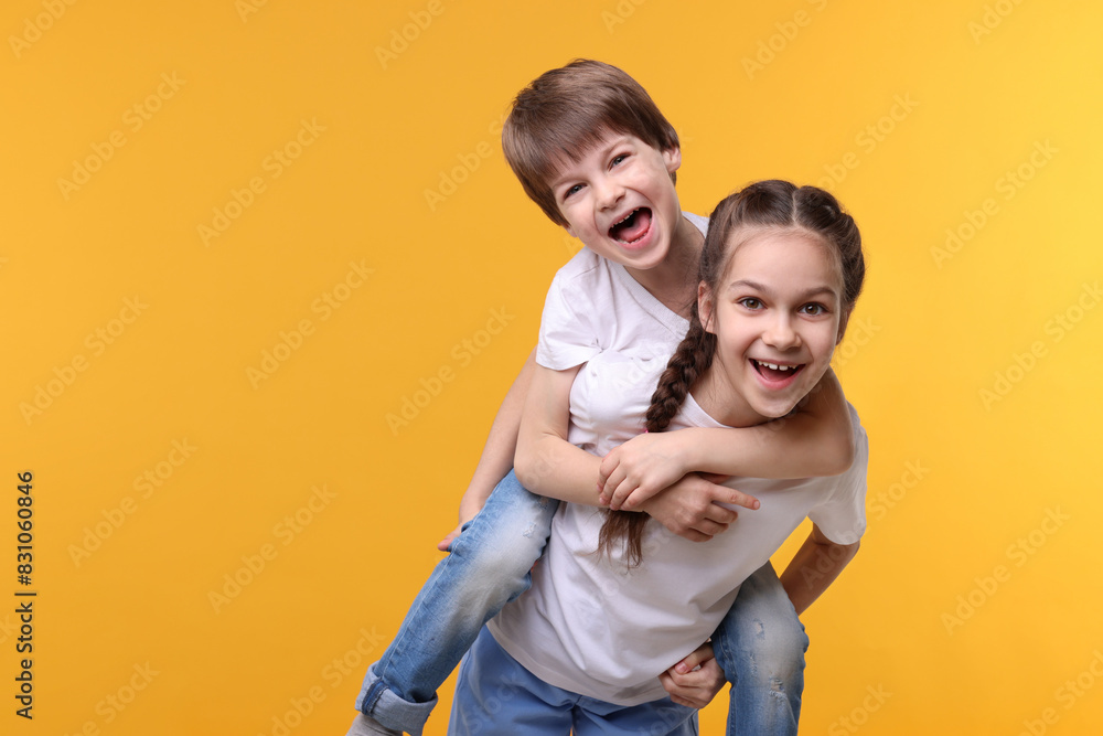 Wall mural happy brother and sister on orange background