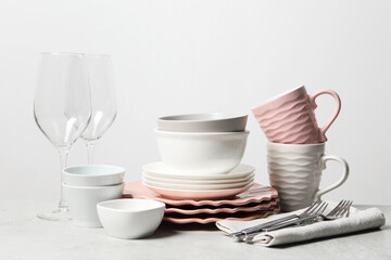 Beautiful ceramic dishware, cups, glasses and cutlery on light grey table