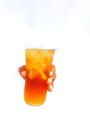 hand holding iced lemon tea in a plastic glass on a white background