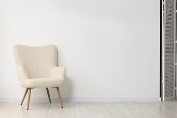 Comfortable armchair near white wall in room, space for text