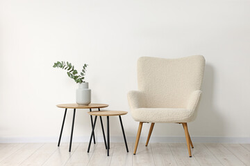 Comfortable armchair, nesting tables and eucalyptus indoors