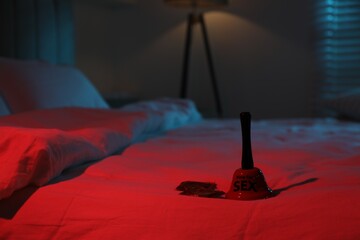 Ring for sex bell and condoms on bed in bedroom at night