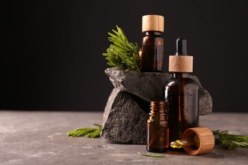 Essential oil in bottles, dropper and rosemary on grey table, space for text