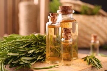 Essential oil in bottles and rosemary on table, closeup