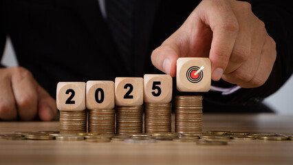  2025 new year budget planning concept. Businessman hand is holding a wooden block with a target...