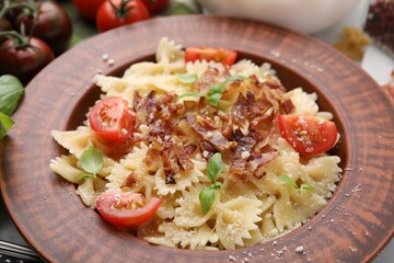 Tasty pasta with bacon, tomatoes and basil on table, closeup