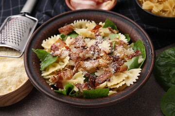 Tasty pasta with bacon and basil on brown table