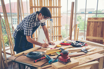 DIY craftsperson asian man working wood heap carpenter objects woodwork desk. Architect man hands...