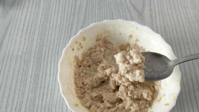 Man eats a mix of oat and millet porridge with a spoon. First person view video