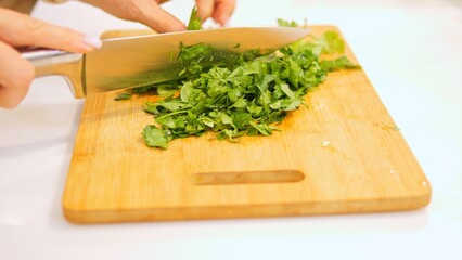 Skilled chef chops vibrant greens on wooden cutting board. Precise movements ensure each leaf is prepared to perfection, enhancing dish with flavor. Aroma of greens fills kitchen, tantalizing senses