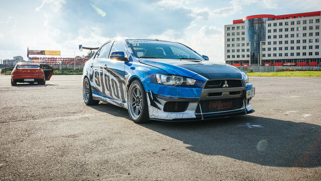 Two Milsubishi Lancer evolution at local track driving event paddock. Evo X parked with light coming from the back. Chaiky, Ukraine - July 20 2014.