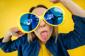 Closeup wide shot fisheye portrait of young beautiful hipster woman in sunglasses showing her tongue