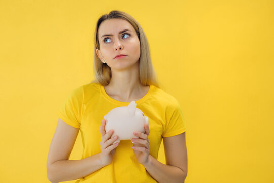 young thoughtful woman feeling sad and whiney with an unhappy look because of financial problems, negative and frustrated attitude. piggy bank concept