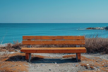 An empty rustic wooden bench faces the calm sea, evoking a sense of loneliness and reflection on the beach