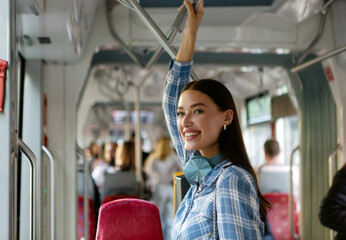 Happy passenger lady standing in modern tram enjoying comfortable ride in public transport indoors,...